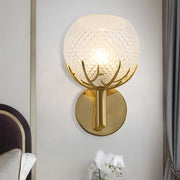 Contemporary gold-toned wall lamp with frosted lattice glass globe and antler-like metal arms for bedroom sconce