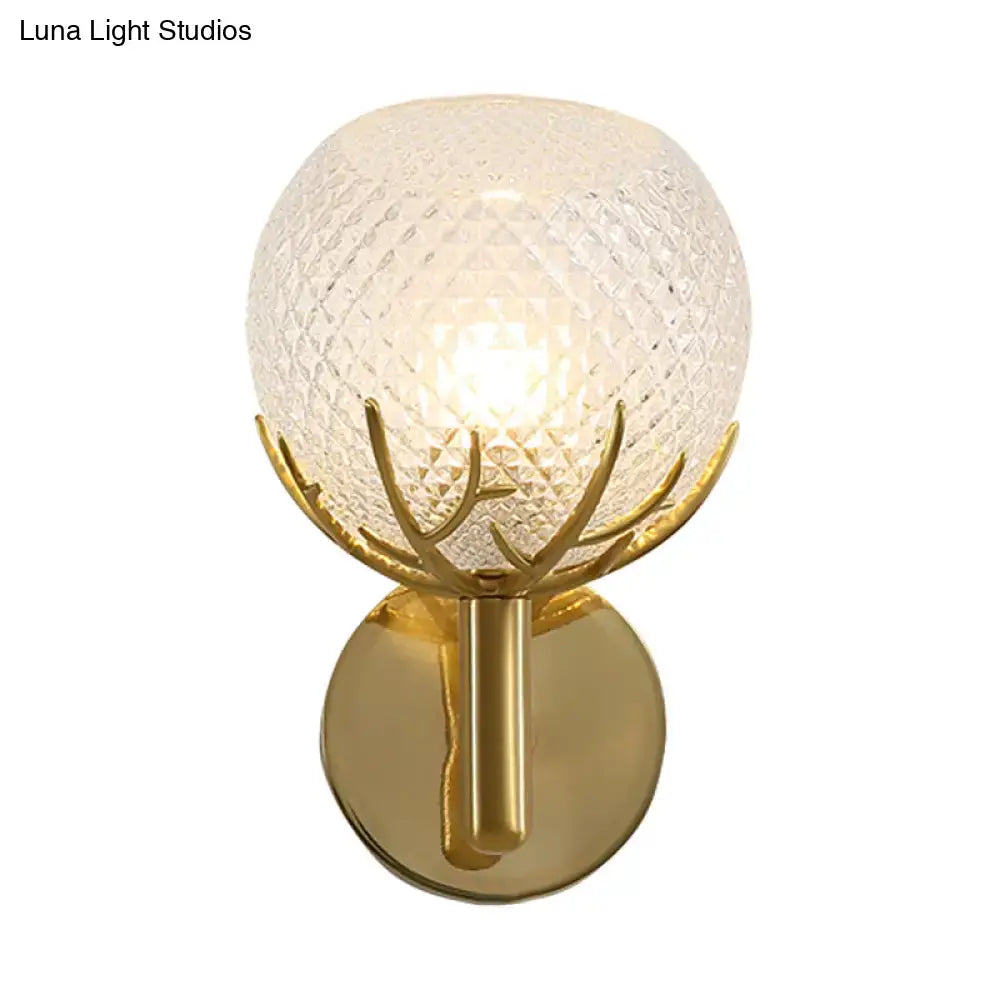 Contemporary brass wall lamp with frosted lattice glass globe and gold-toned antler-like metal accents for bedroom sconce