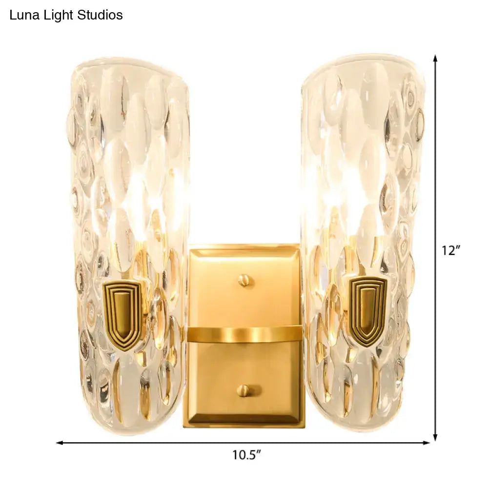 Contemporary brass wall sconce with gold finish and clear water glass shades featuring hammered texture for bedroom use