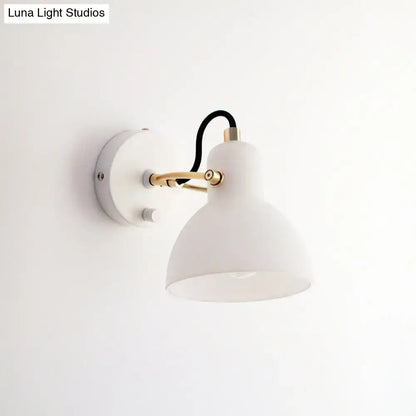 Contemporary wall lamp with white glass domed shade and brass-finished articulated arm for bedroom use