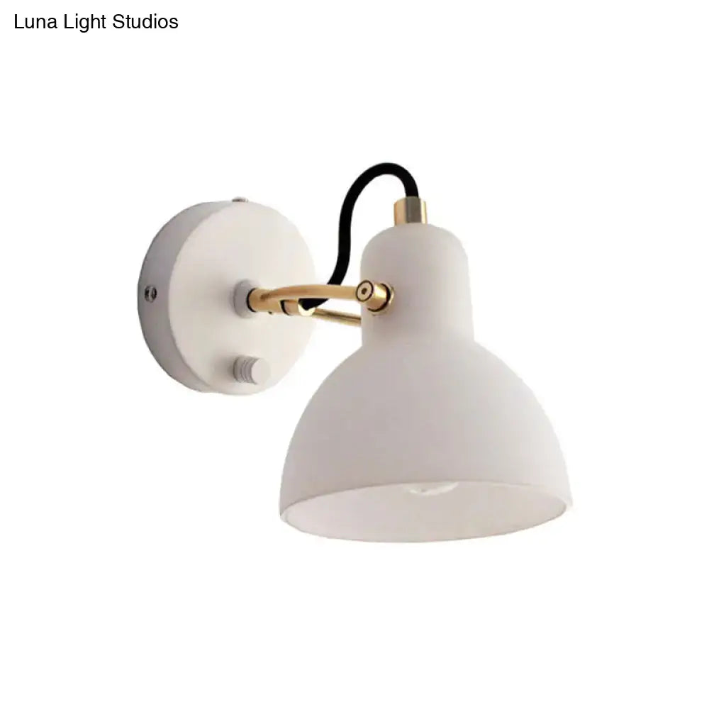 Contemporary wall lamp with white glass domed shade, brass articulated arm, and black cord for bedroom use