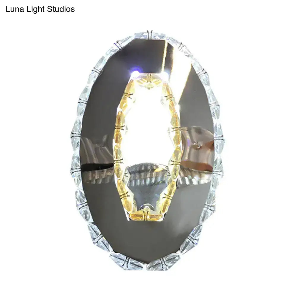 Contemporary chrome crystal oval light fixture with a beaded silver frame and warm white amber crystal chandelier reflection