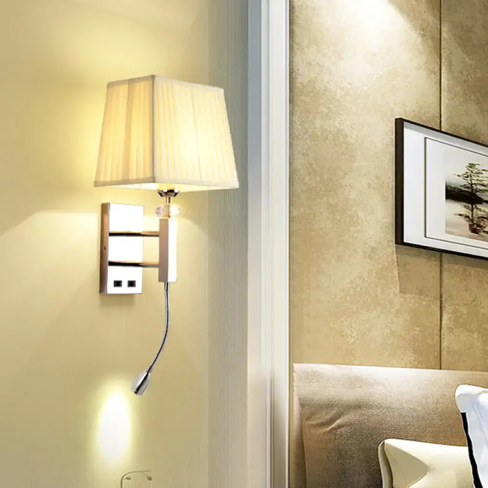 Cream-colored pleated fabric lampshade on a contemporary chrome light fixture with spot light and integrated outlets