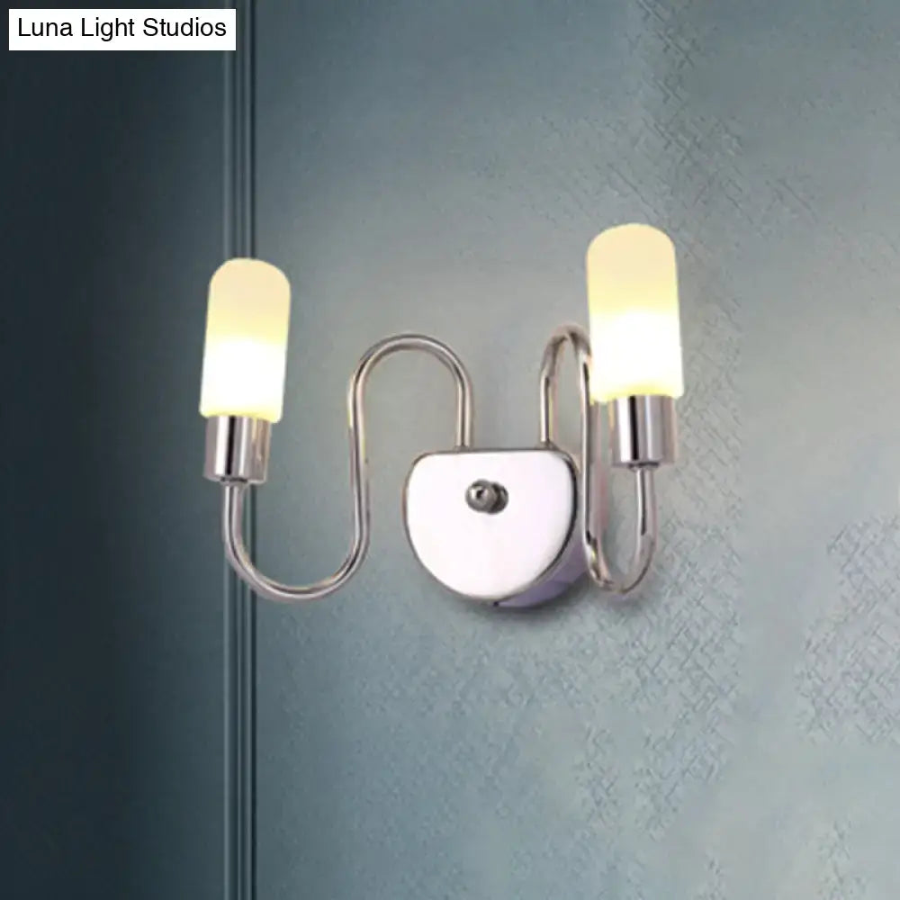 Contemporary chrome milk glass pill bedroom wall light with two frosted glass shades emitting a warm glow