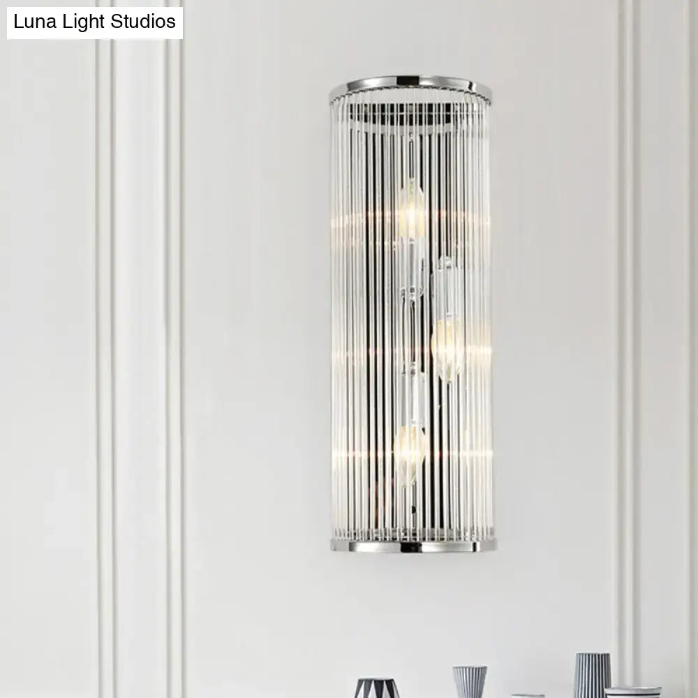 Contemporary chrome wall sconce with clear crystal tube and three exposed light bulbs for bedroom lighting