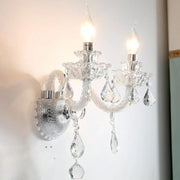Contemporary clear faceted crystals wall sconce with two lit candle-shaped bulbs and dangling teardrop crystals