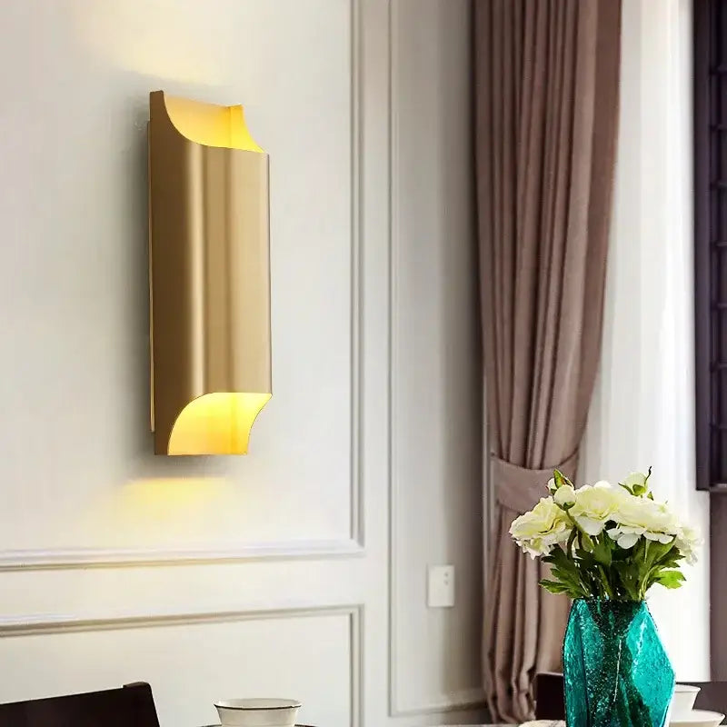 Contemporary copper brass wall sconce with gold-toned curved design and warm ambient lighting for living room decorbites contemporary copper