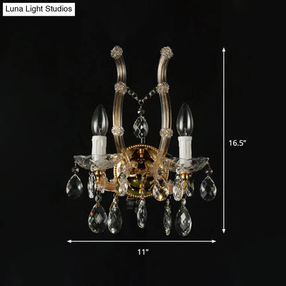 Elegant gold-toned crystal deco wall sconce with amber glass and candle bulbs featuring a fixture width suitable for bedrooms