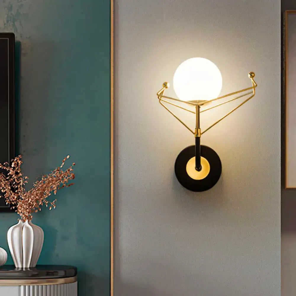 Contemporary gold-toned geometric wall sconce with cream glass orb and black base for bedroom light fixture