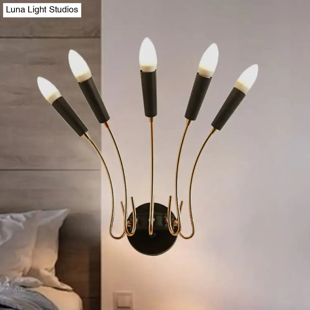Contemporary metal sconce with five curved gold-toned arms and black cylindrical bases with illuminated white bulbs