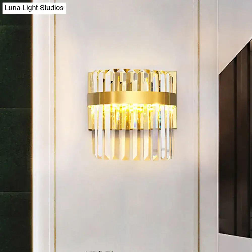 Contemporary gold-toned demilune cylinder wall light with vertical crystal prisms and illuminated band for living room