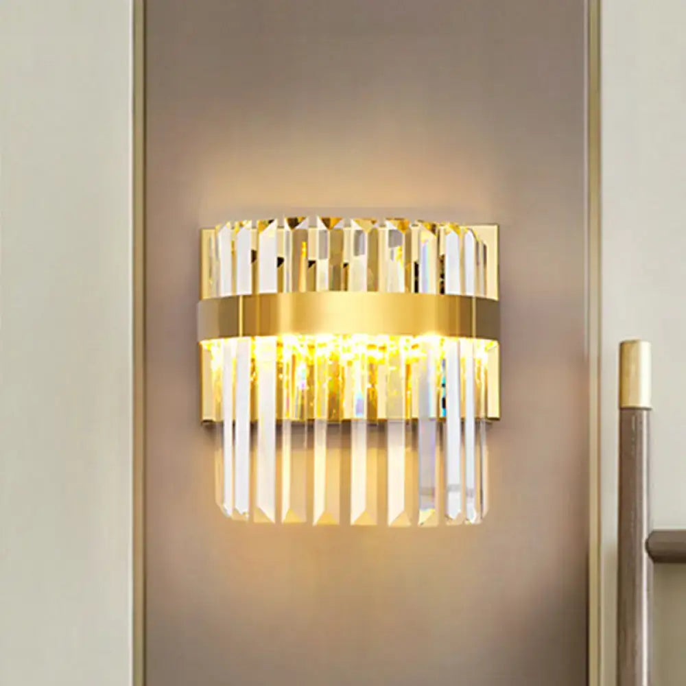 Contemporary gold-toned demilune cylinder wall light with vertical crystal prisms and warm glowing wall light for living room