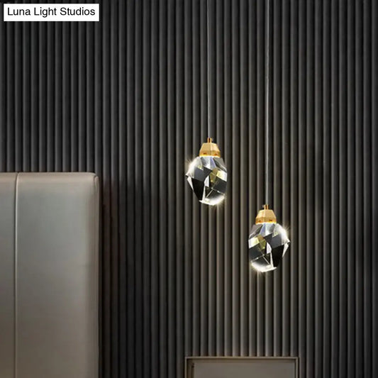 Two elegant DecorBites™ crystal stone-shape pendant light fixtures with gold tops hang against a dark ribbed wall