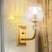 A gold-toned wall light with a polished brass arm and clear lattice glass dome foyer wall globe
