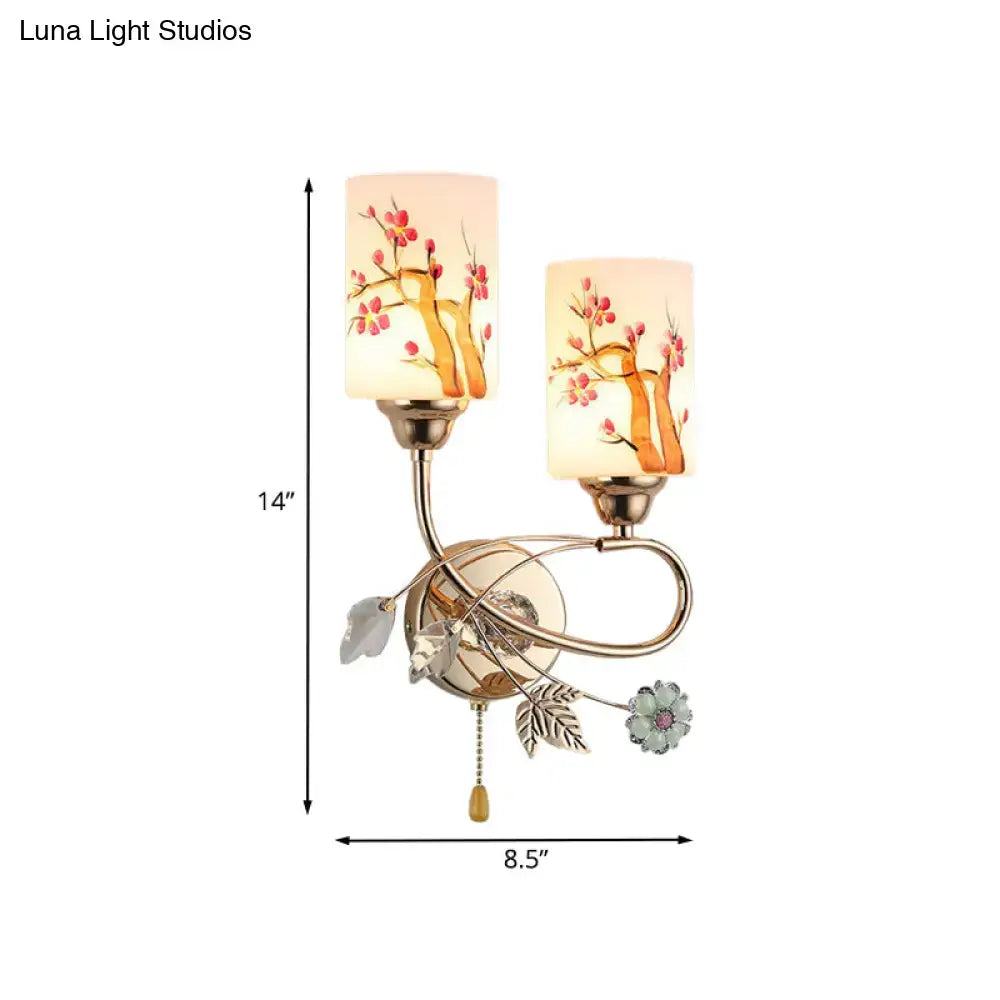 Contemporary wall lamp with gold finish brass frame and cream glass shade featuring painted cherry blossom design