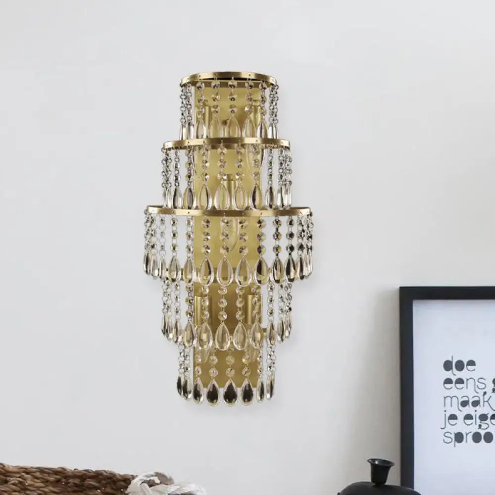 Contemporary gold layered bedside wall lamp with teardrop crystals and cascading tiers in clear crystal design
