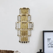 Contemporary gold layered bedside wall lamp with teardrop crystals and cascading tiers in clear crystal design
