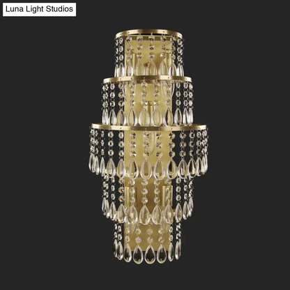 Contemporary gold layered bedside wall lamp featuring a tiered crystal design with teardrop crystals and metal frames