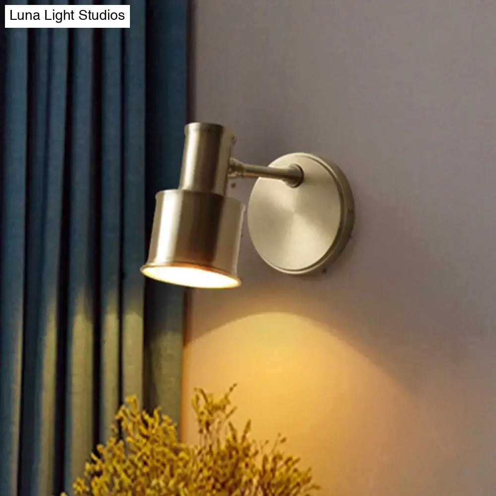 Brass-finished adjustable metal cylinder wall spotlight with cylindrical head and circular base for bedroom use