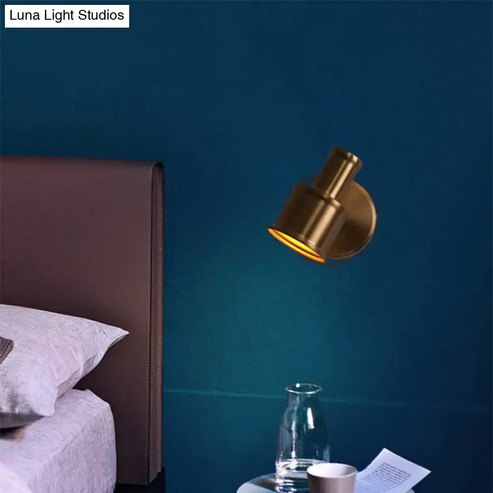 A sleek gold metal cylinder wall sconce with adjustable arm for bedroom reading spotlight use