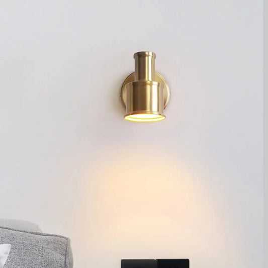Contemporary brass finished metal cylinder wall sconce with warm focused illumination for bedroom spotlight use