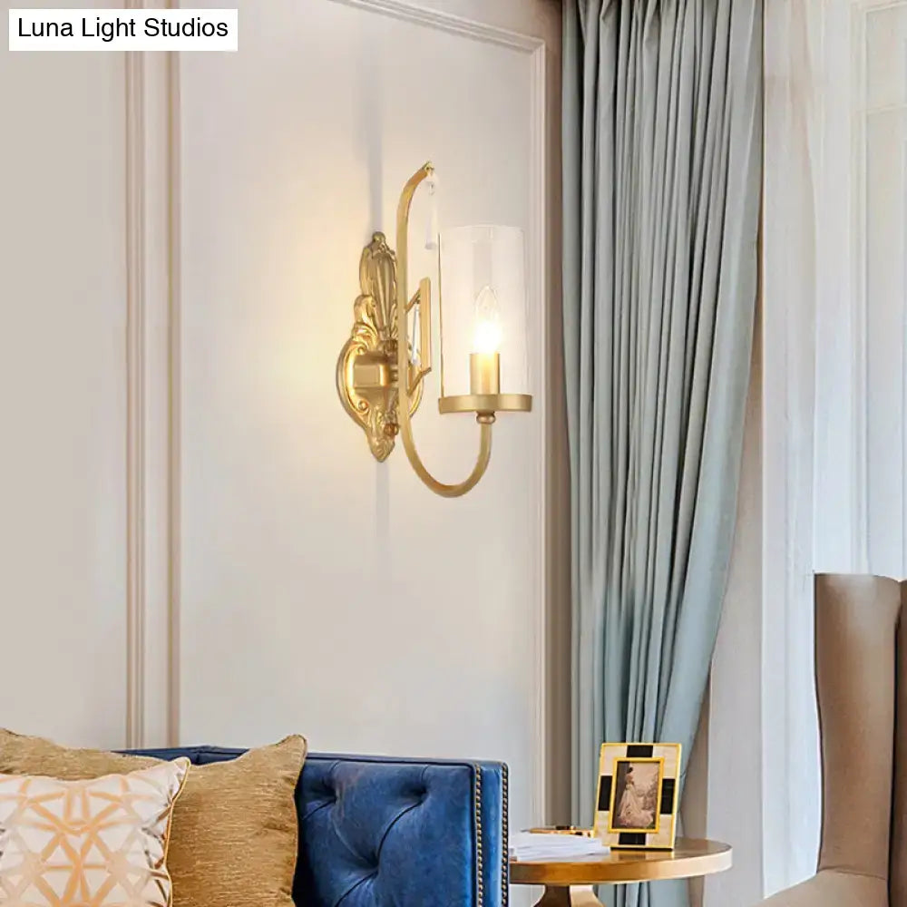 Contemporary gold wall light bedroom sconce with clear glass shade and exposed candle-style bulb in gold tone