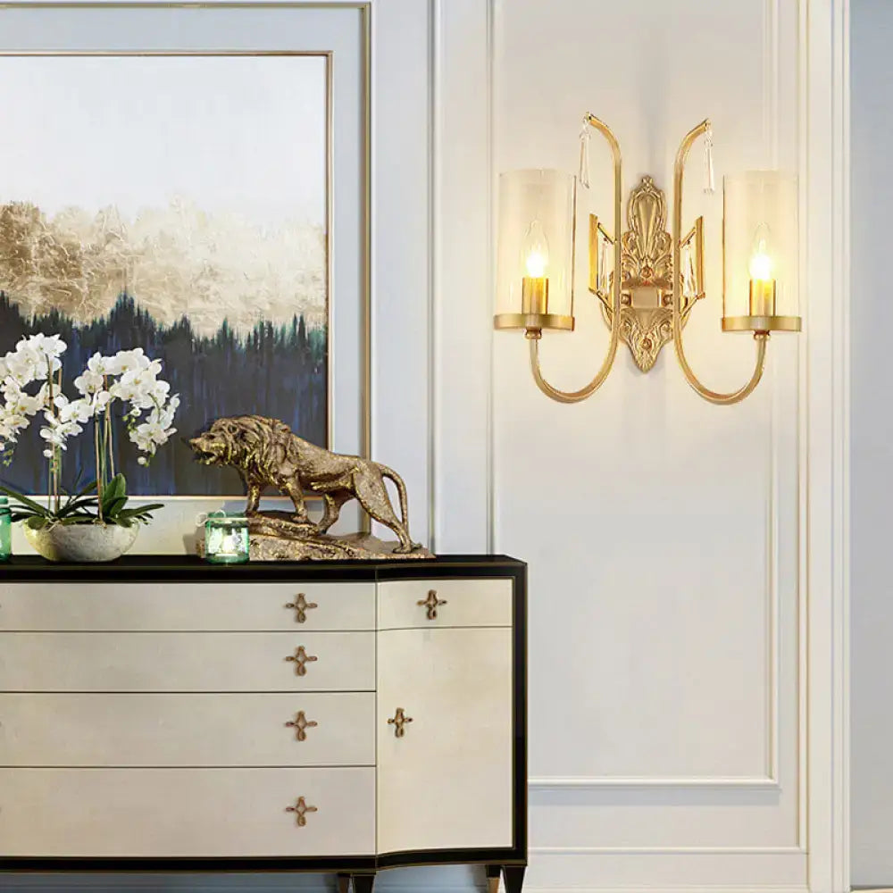 Gold-toned ornate wall light with two curved arms and frosted clear glass shade for contemporary bedroom use