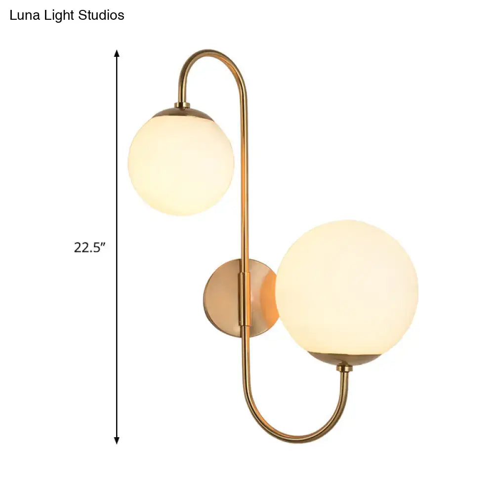 Contemporary gold wall sconce with brass finish and two spherical opal glass shade globes for bedroom lighting