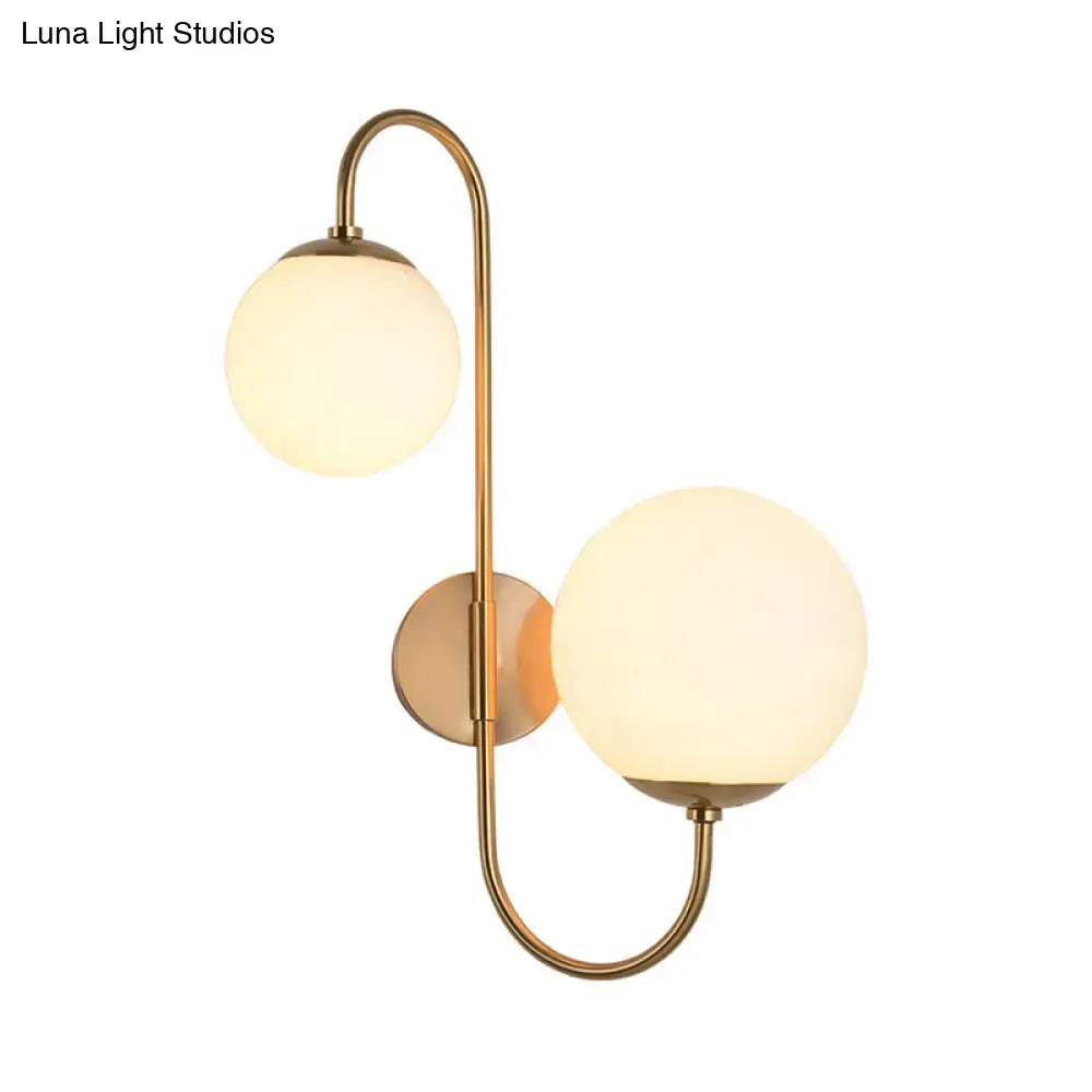 Contemporary brass-finished wall sconce with two frosted opal glass shades for bedroom lighting