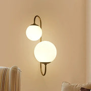Brass-finished contemporary gold wall sconce with two frosted opal glass shade globes for bedroom lighting