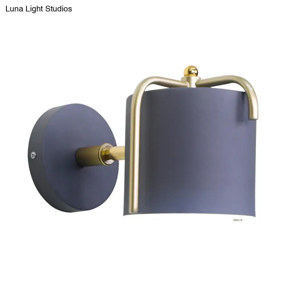 Contemporary green grey sconce with a matte navy blue cylindrical shade and brass accents for bedroom lighting