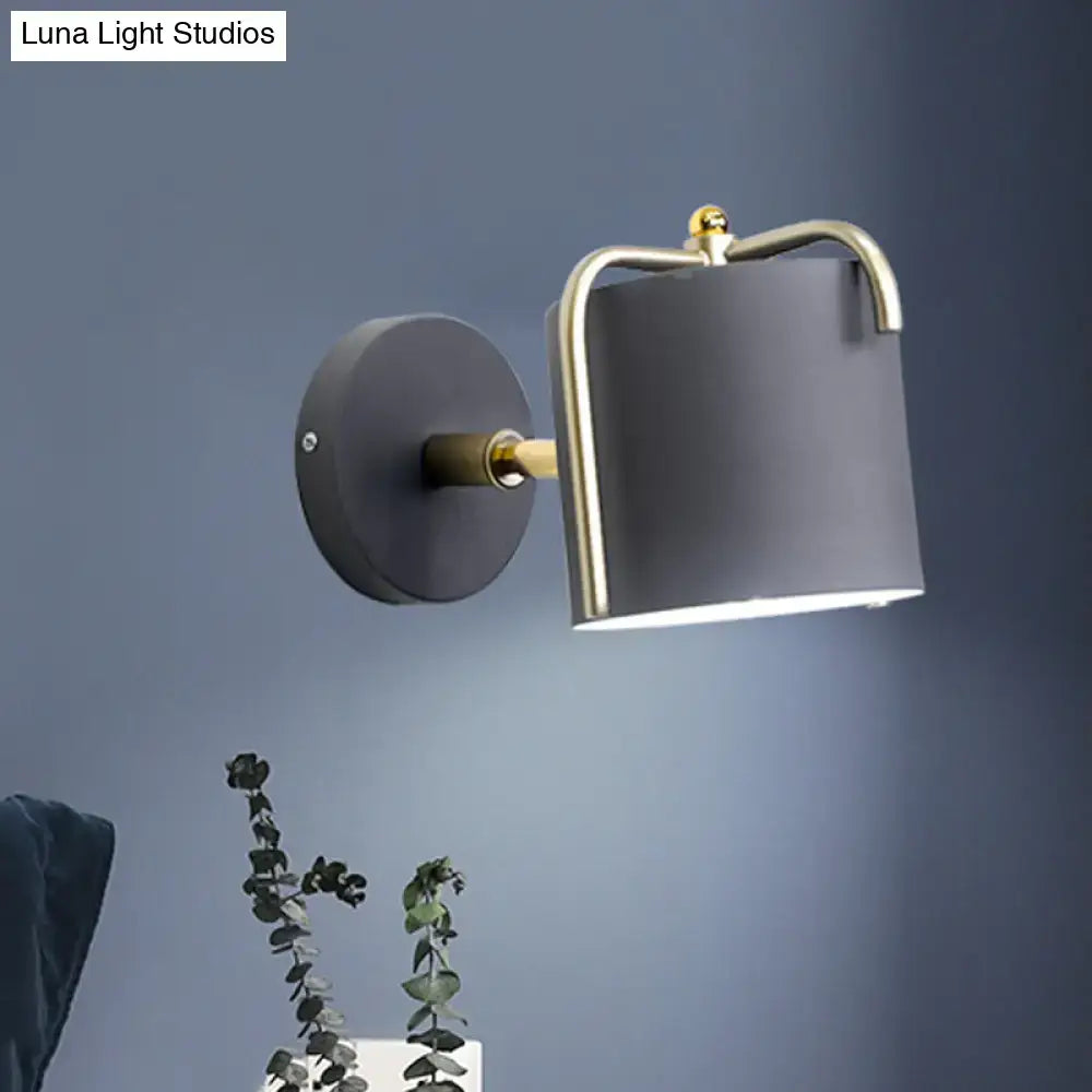 Contemporary green grey sconce with a matte black cylindrical shade and brass metal frame for bedroom lighting