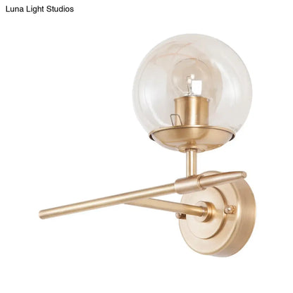 DecorBites™ DecorBites™ Contemporary Hand Blown Glass Wall Light with Brass Globe and Crossed Arm