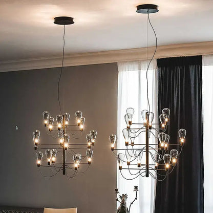 Two contemporary iron glass chandeliers with black metal frames and clear glass shades hang in a foyer setting