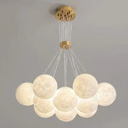 A gold modern ceiling chandelier with textured moon-like spherical pendant lights decorbites contemporary led decor