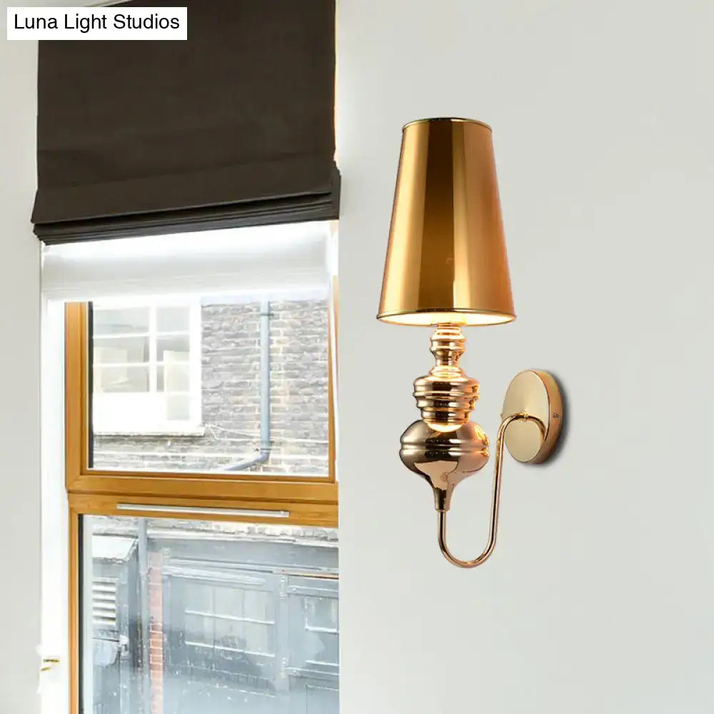 Contemporary brass-finished wall mount light with tapered cylindrical fabric shade and ornate detailing for bedroom use