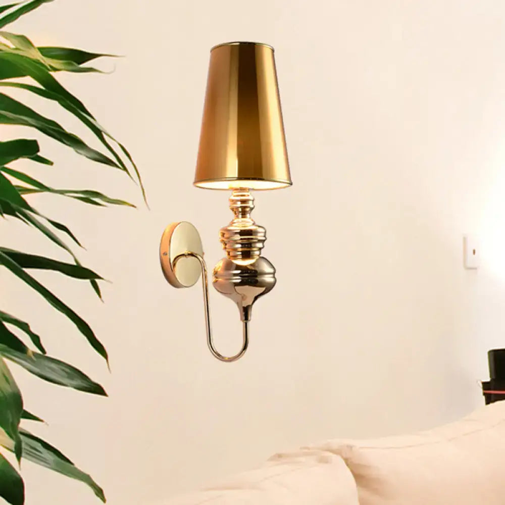 Contemporary gold-toned wall mount light with polished metallic finish and conical lampshade for bedroom use