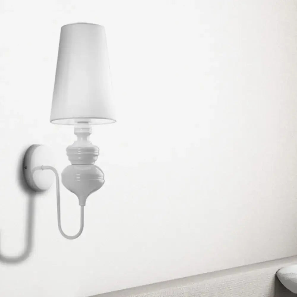 White ceramic wall mount light with a tapered fabric lampshade and curved arm for contemporary bedroom use