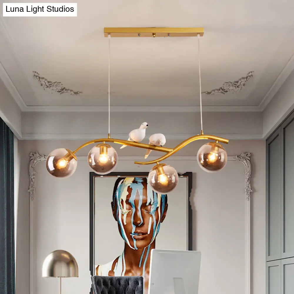 مصباح معلق عصري على شكل فرع معدني من DecorBites™ - 4 مصابيح باللونين الأسود والذهبي مع ديكور الطيور وغطاء زجاجي رمادي دخاني/كونياك