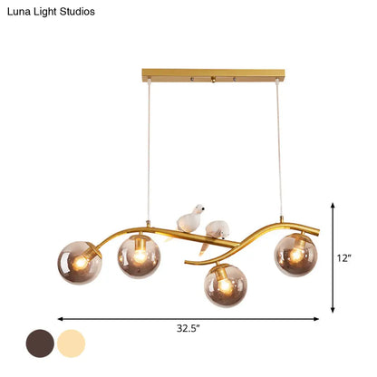 مصباح معلق عصري على شكل فرع معدني من DecorBites™ - 4 مصابيح باللونين الأسود والذهبي مع ديكور الطيور وغطاء زجاجي رمادي دخاني/كونياك