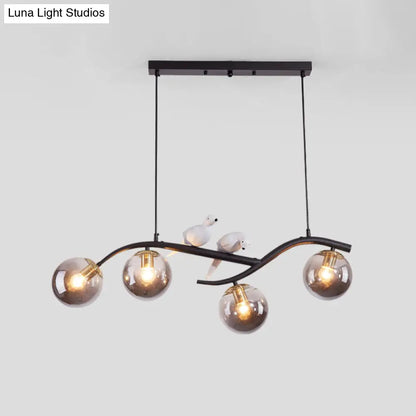 مصباح معلق عصري على شكل فرع معدني من DecorBites™ - 4 مصابيح باللونين الأسود والذهبي مع ديكور الطيور وغطاء زجاجي رمادي دخاني/كونياك