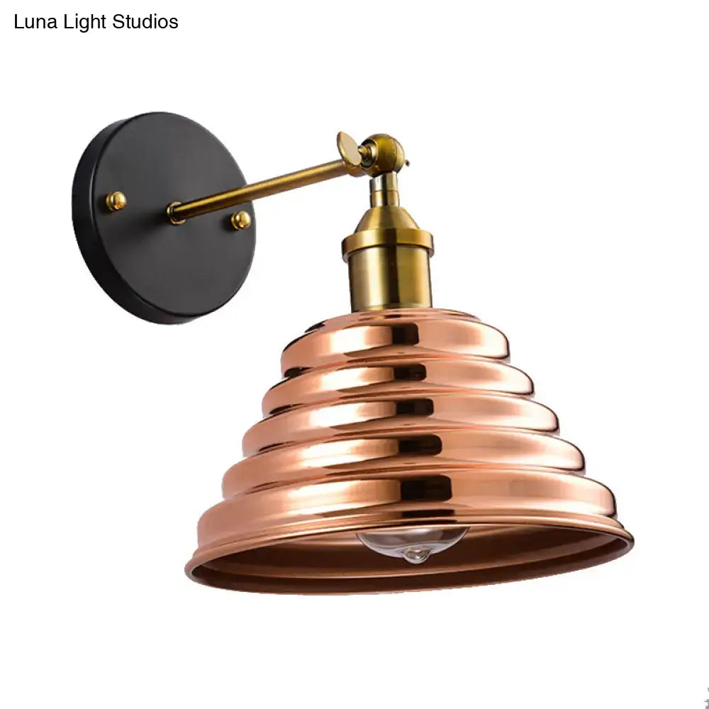 Contemporary rose gold ribbed wall sconce with copper-toned tiers, brass arm, and black mounting plate for bedroom lighting