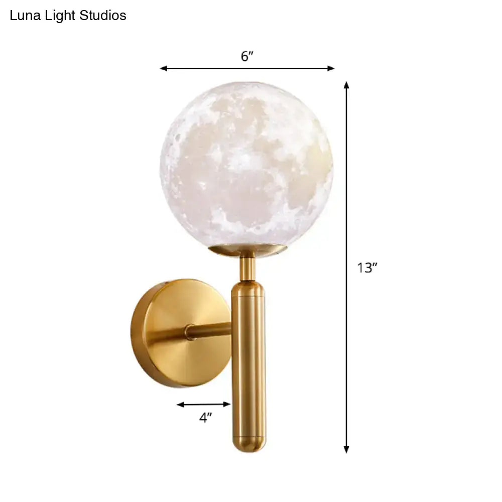 A sleek gold-toned contemporary white glass wall sconce with a moon phase globe for bedroom lighting fixture
