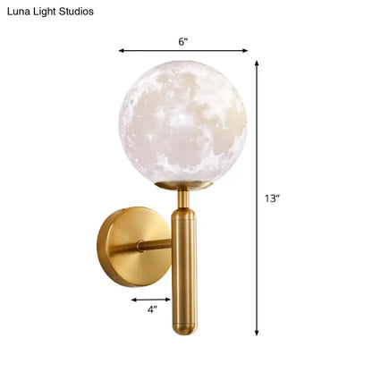 A sleek gold-toned contemporary white glass wall sconce with a moon phase globe for bedroom lighting fixture