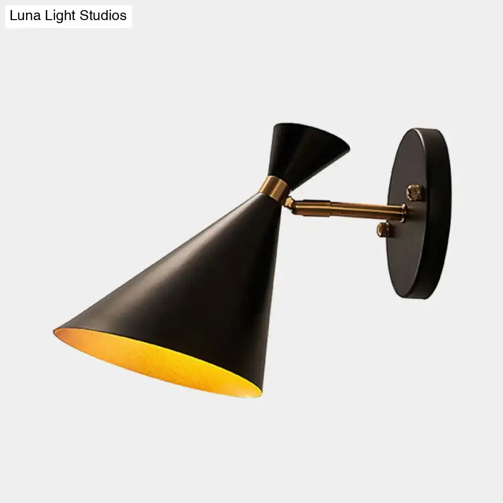 Contemporary black wall sconce with brass adjustable arm and gold interior lining for bedroom lighting