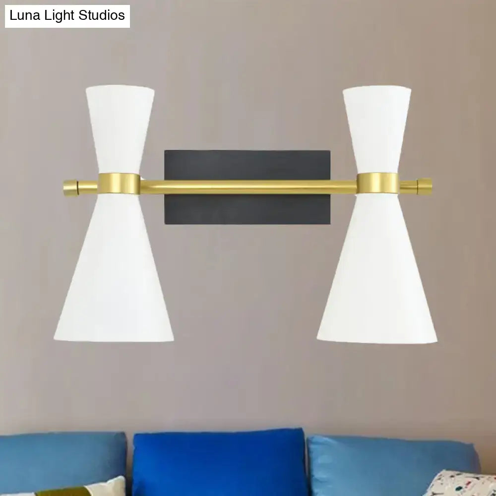 Modern dual-light wall sconce with white conical shades and brass-finished adjustable arm for bedroom lighting