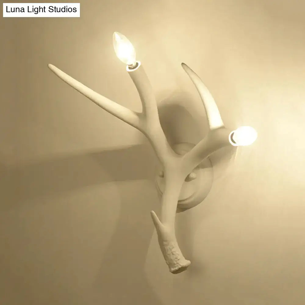 Contemporary white resin antler wall sconce with two illuminated candle-style bulbs for restaurant dining room use