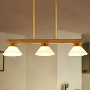 Contemporary wood linear island ceiling light featuring warm tones, frosted glass shades, and gold black brass accents