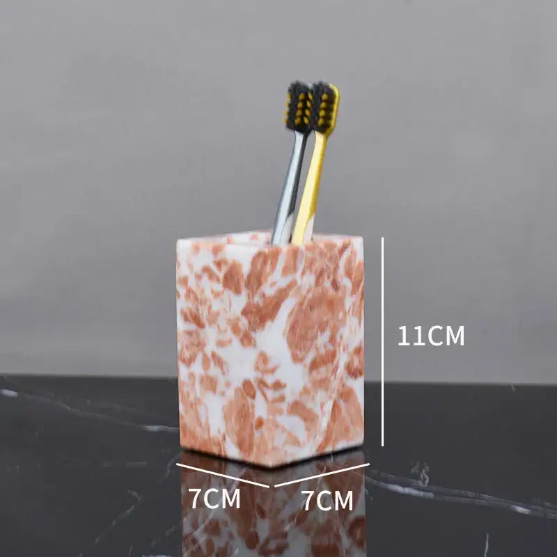 A square coral pink marble bathroom toothbrush holder with white accents holding two toothbrushes from decorbites coral pink set