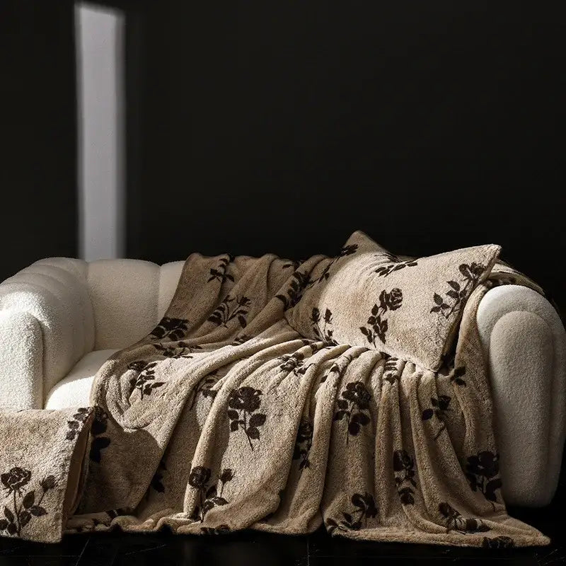 Beige faux rabbit plush throw blanket with dark brown rose embroidery draped over cream sofa for cosy faux decorbites